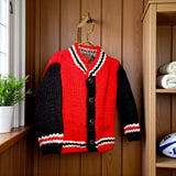Red and black tartan handknitted alpaca wool toddler jacket in lifestyle setting