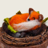 Close view of the sleeping fox's face, ears and ecru-tipped tail above the twig wreath