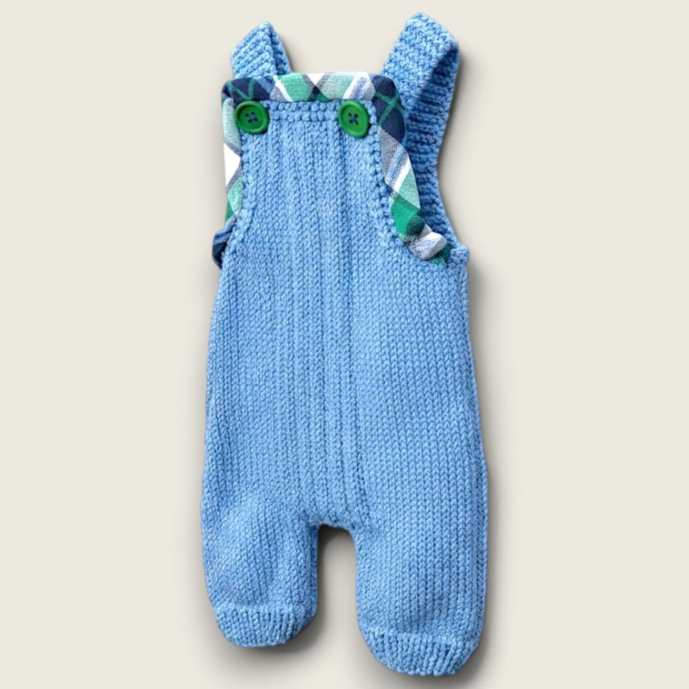 Handknitted merino wool baby dungarees with green and navy tartan trim and wooden buttons, handmade in the Boyne Valley, Ireland.