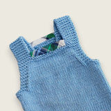 Back of blue merino baby dungarees showing straps and printed tartan trim.