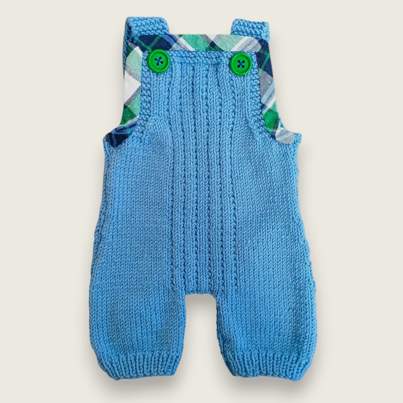 Blue merino baby dungarees with printed tartan trim and green buttons.