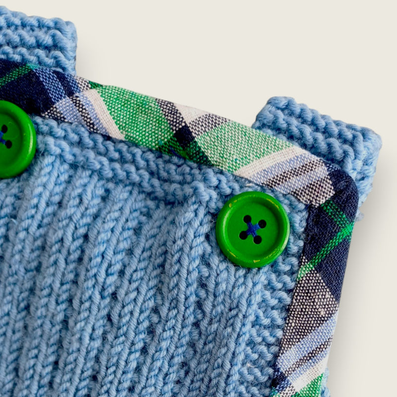 Blue merino baby dungarees showing green buttons and printed tartan trim.