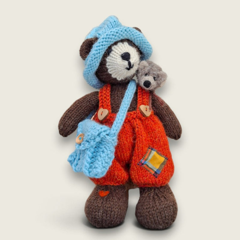 Bracken Moss handmade Pebblewood collectible bear wearing rust dungarees and blue knitted accessories with a needle-felted hedgehog on his shoulder.