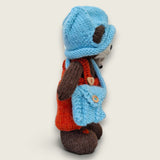 Right side view of Bracken Moss, a handmade Pebblewood collectible bear wearing rust dungarees, blue knitted hat and satchel.