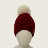 Burgundy handknitted alpaca and wool hat with a mink-coloured faux fur pompom, front view