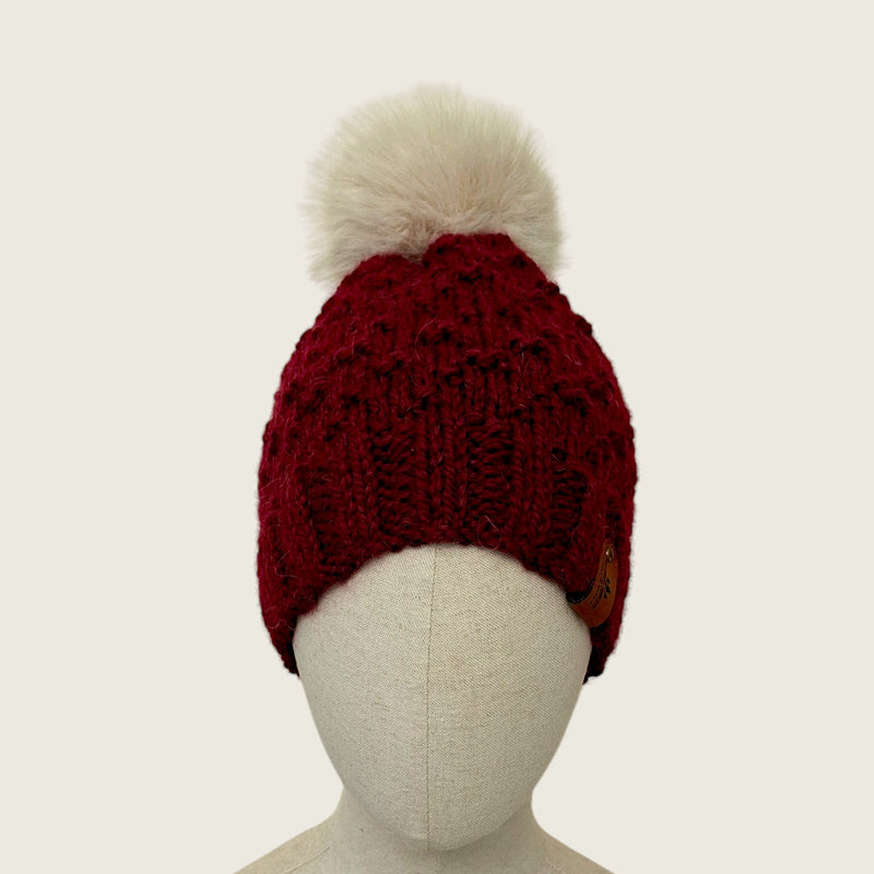 Burgundy handknitted alpaca and wool hat with a mink-coloured faux fur pompom, front view
