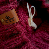 Close-up of the textured knit, leatherette tag and the ribbon that holds the pompom