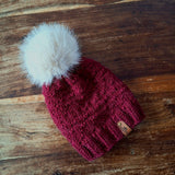 Close-up of the textured knit, leatherette tag and the ribbon that holds the pompom