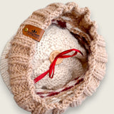 Inside of the hat, showing the leatherette tag, wooden button and ribbon that hold the pompom