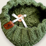 Close-up of the textured knit, leatherette tag and the ribbon that holds the pompom