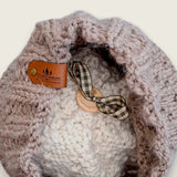 Inside of the hat, showing the leatherette tag, wooden button and ribbon that hold the pompom