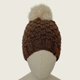The dark brown hat on a mannequin, showing its full shape from brim to pompom
