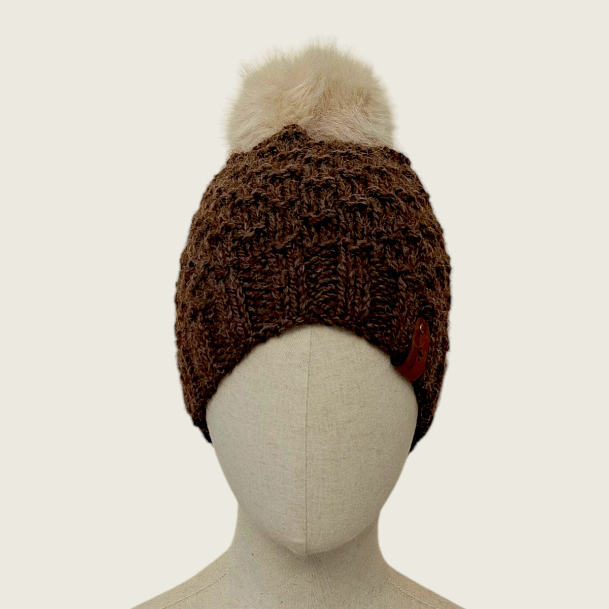 Dark brown handknitted alpaca and wool hat with a mink-coloured faux fur pompom, front view