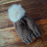 The dark brown knitted hat lying flat on a dark wooden table