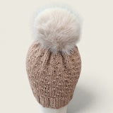 Back view of the fawn knitted hat with a pale faux fur pompom
