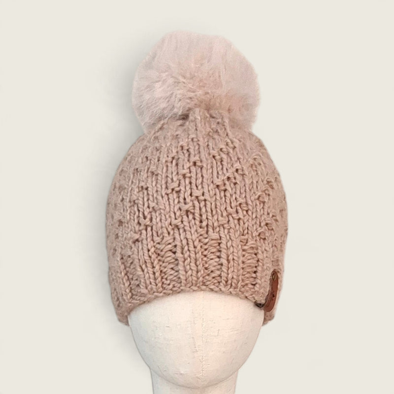 Fawn handknitted alpaca and wool hat with a mink faux fur pompom on a mannequin head