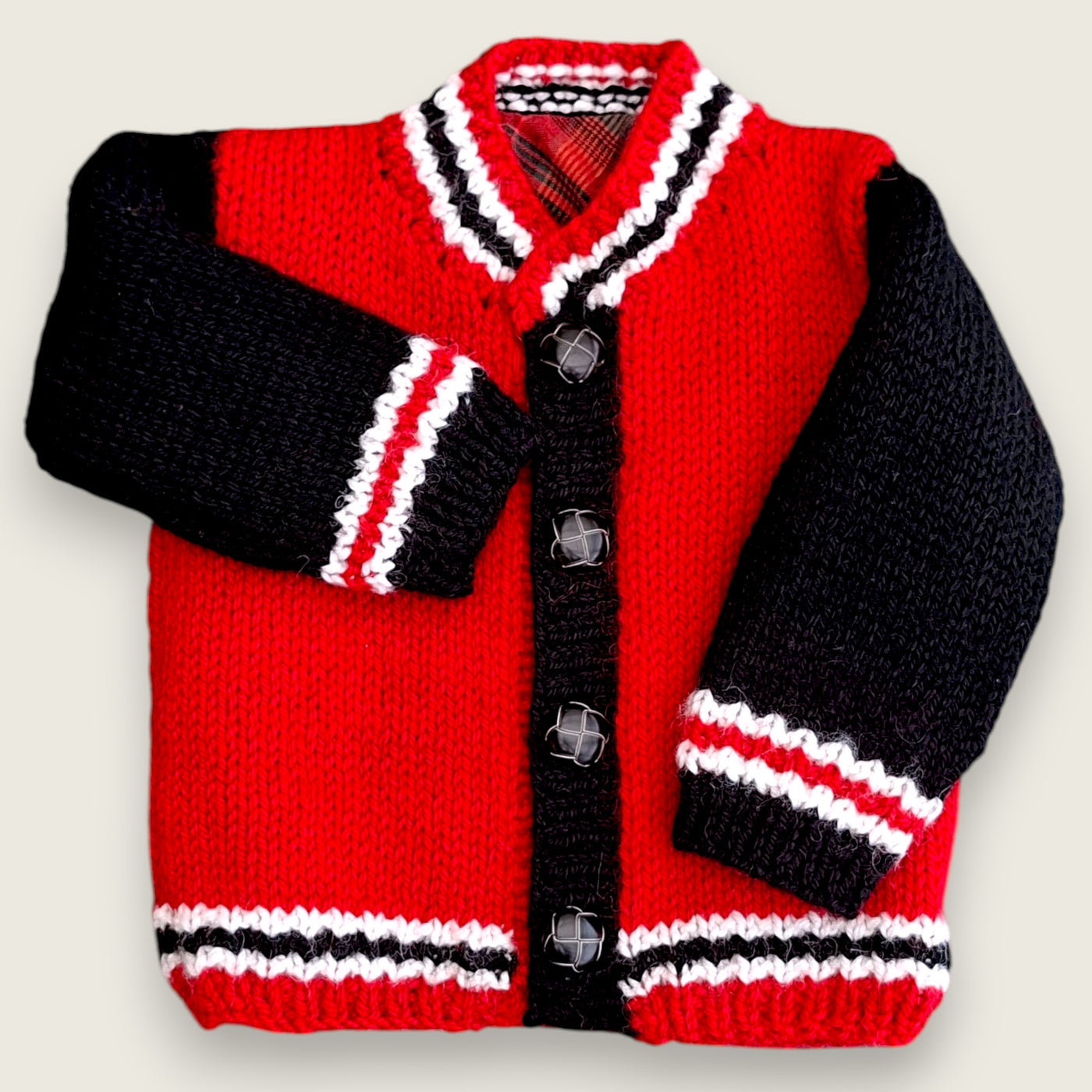 Front view of red and black handknitted alpaca wool toddler jacket with tartan lining