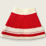 Back view of red and ivory handknitted merino wool baby capelet with patterned border.