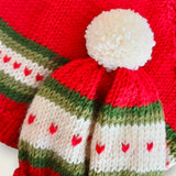 Red merino newborn cardigan and matching handknitted hat laid flat