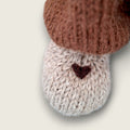 Close-up of the needle-felted heart detail on the right paw of Hazel Hollow, a hand-knitted Pebblewood collectible bear.