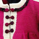 Hand-covered buttons and braided trim on magenta merino baby coat