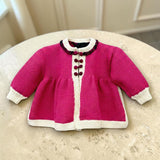Magenta merino wool baby matinee coat styled in a cream home setting