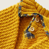 Close-up of mustard wool jumper neckline, wooden buttons and tartan trim.