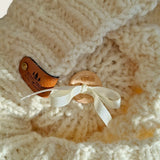 Inside of the hat, showing the wooden button and ribbon that hold the pompom