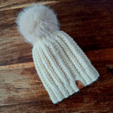 The natural knitted hat lying flat on a dark wooden table