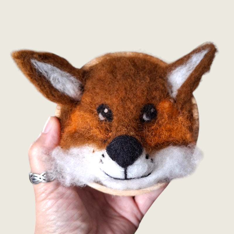 Hand needle-felted red fox face mounted in a small wooden bowl, shown in hand to demonstrate its scale.