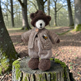 Pebblewood bear wearing fawn bee cardigan in a woodland setting
