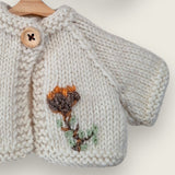 Close-up of hand-embroidered flower on ecru wool bear cardigan