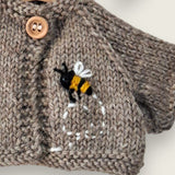 Close-up of embroidered bee and flight path on fawn wool bear cardigan