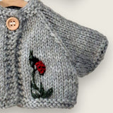 Close-up of hand-embroidered ladybird and leaf on light grey wool cardigan