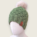 Side view of the sage green textured hat, showing the leatherette tag at the brim