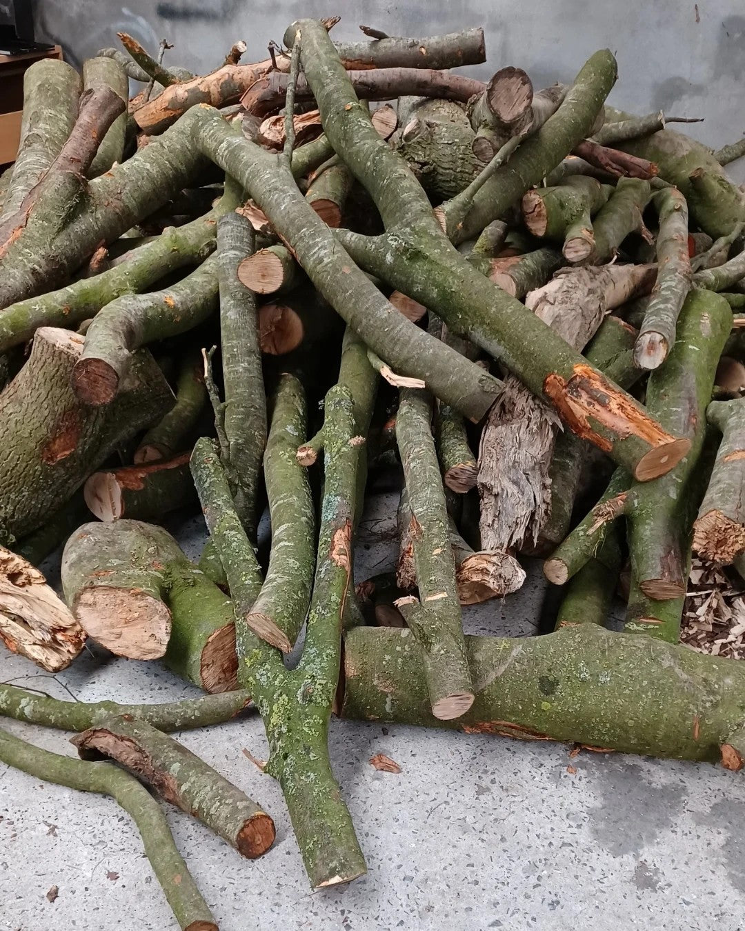 A pile of freshly cut branches with green bark, come down in Pebblewood and waiting to be turned.