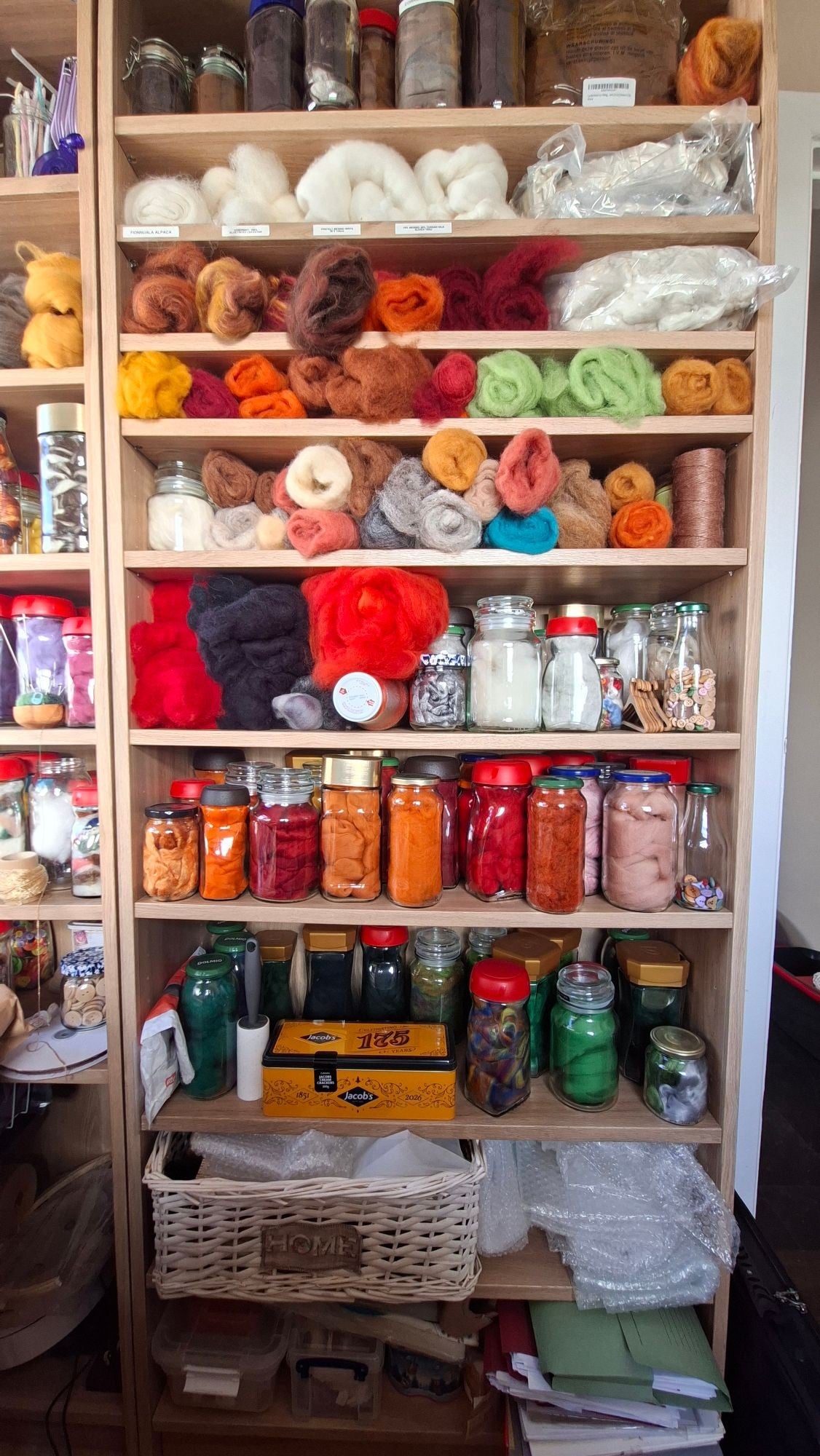 Workroom shelves filled with jars and tins of dyed wool fibre in every colour.