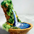 Side view of The Living Fall, a handcrafted 3D felted wool sculpture showing the waterfall flowing into a pool within a wooden bowl.