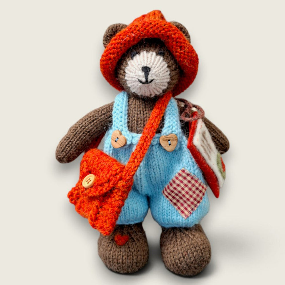 Thorne Ash, Pebblewood collectible bear and Village Messenger, wearing blue dungarees with a rust knitted hat and satchel, carrying his handmade felt envelope and letter.
