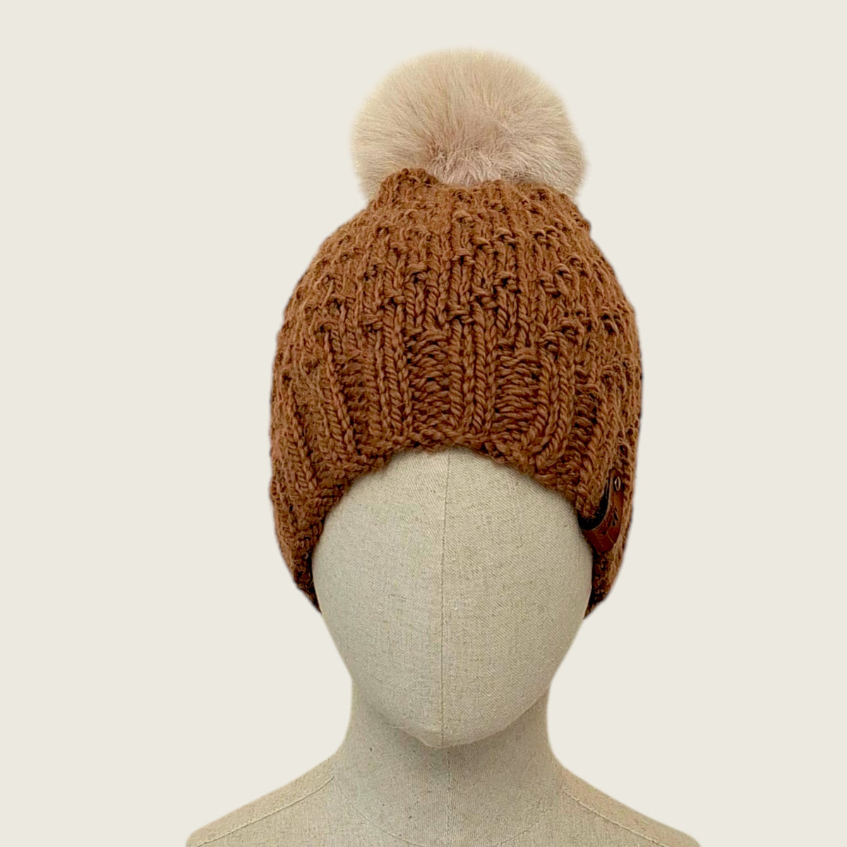 The toffee hat on a mannequin, showing its full shape from brim to pompom