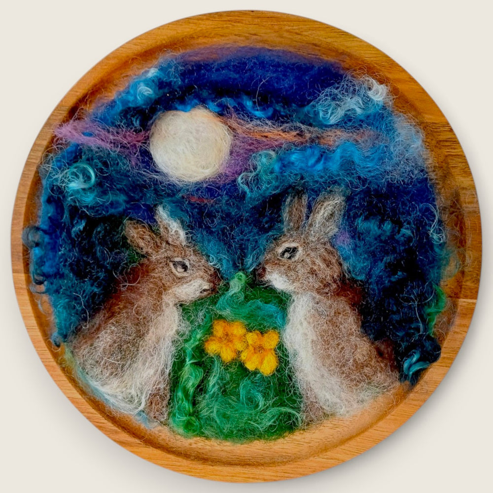 Needle-felted wool picture of two rabbits beneath a full moon, handcrafted in the Boyne Valley, Ireland and mounted on a round wooden plaque.