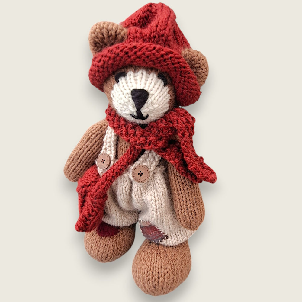 Willow Hearth, a large hand-knitted Permanent Resident of Pebblewood, wearing cream dungarees with a rust-red hat, scarf and satchel.