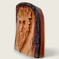 Left-side view of Woodland Face hand-carved in lime wood, showing the retained live edge and carved profile.